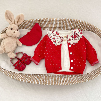 木のテーブルに並べられた赤い子供用カーディガン  