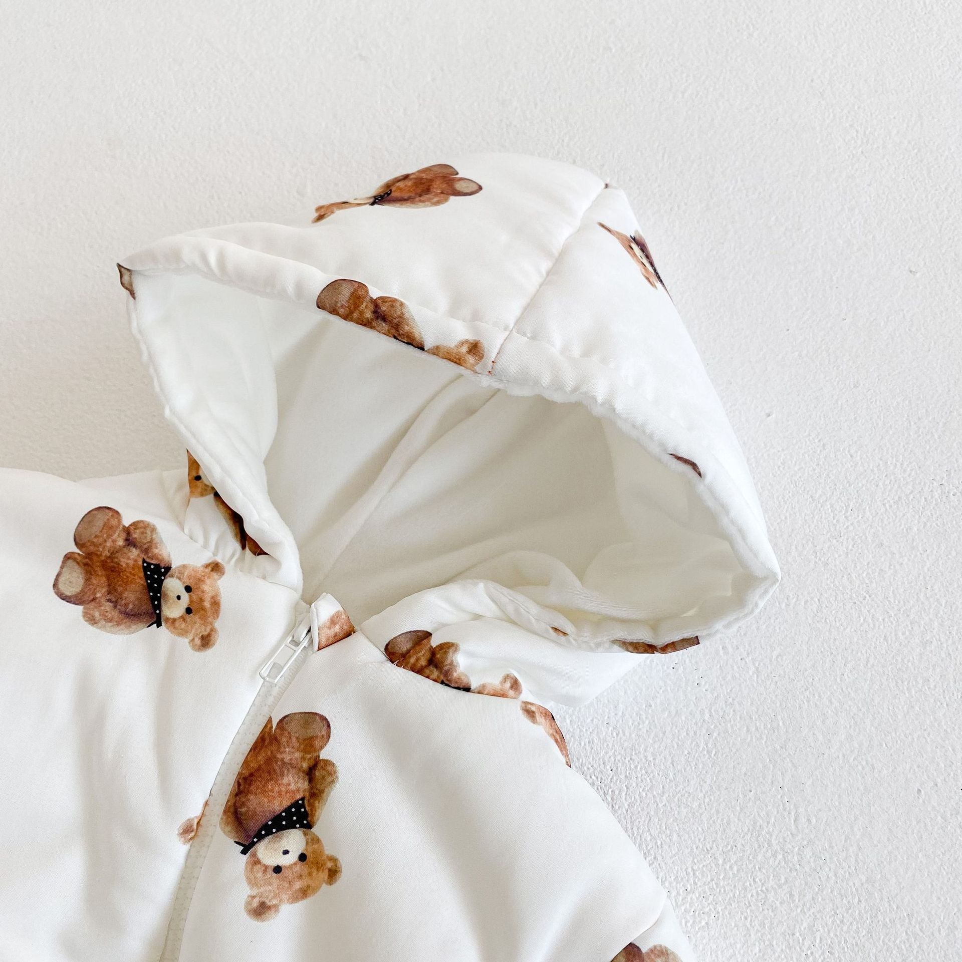 内側のふわふわ裏地が見えるくま柄フード部分を大きく写したベビーカバーオールのフードクローズアップ
