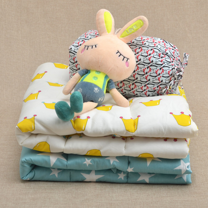 王冠柄デザインのベビーキルトブランケットを重ねて積み、その上にぬいぐるみを置いたやさしい雰囲気の写真（ベビーキルト 王冠柄 出産祝い）
