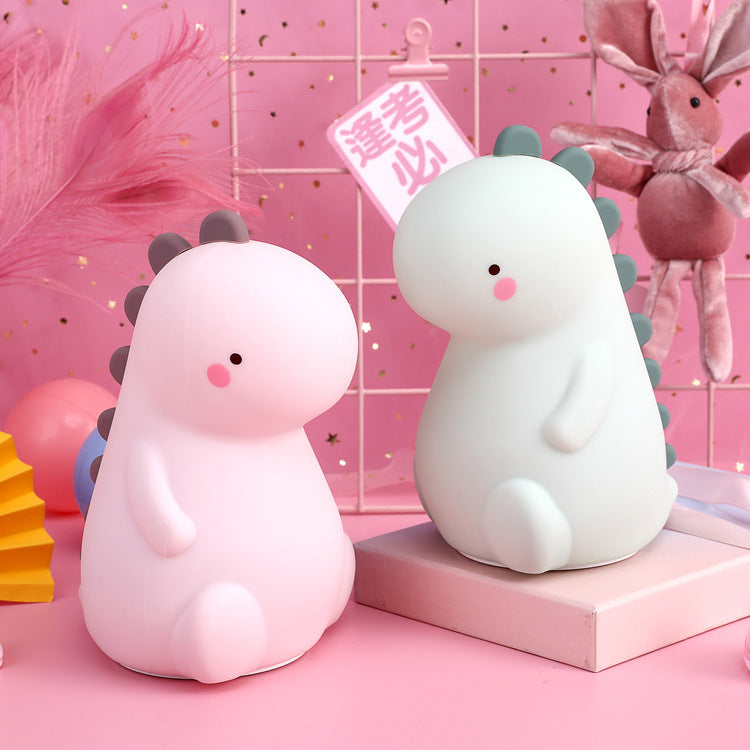 寝室のベビーベッド横でやさしく光る恐竜ナイトライトのイメージ（夜間の授乳・おむつ替え用ライト）
