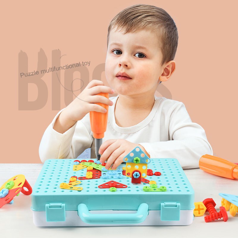 電動ドリルを持った幼児が、水色のボードにカラフルなネジブロックで家や花の模様を作っている様子
