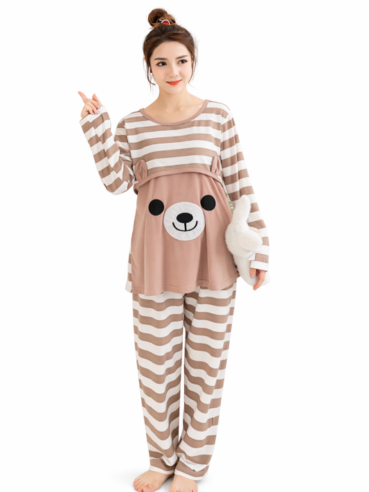 ベージュ×ホワイトのボーダー柄マタニティパジャマを着た女性が、白い背景の前でぬいぐるみを抱えながら立っている全身写真。
