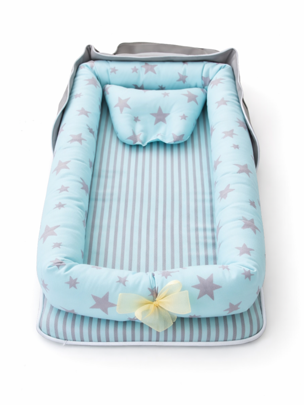 ブルー×グレーの星柄ベビーネスト（クッション枕付き）が、白背景のスタジオ撮影で縦向きに配置され、先端に淡いイエローのリボンが付いている商品画像。
