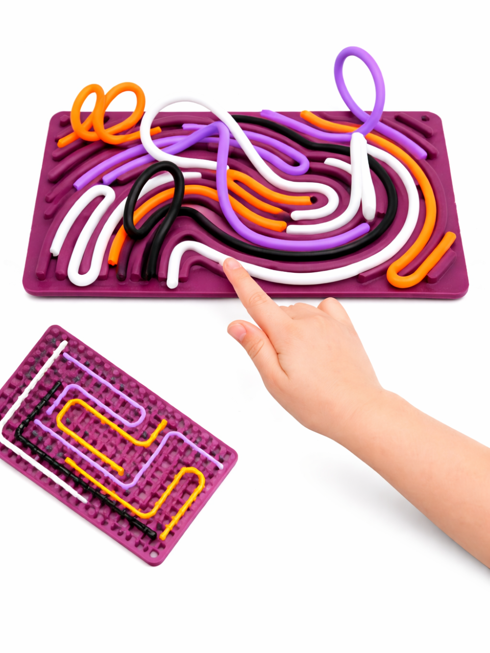白背景のスタジオ撮影。パープルのシリコン迷路ボードに白・黒・オレンジ・紫のチューブが通され、指でチューブを押して遊ぶ様子が写っている。左下に別パターンのボード（ミニ画像）も配置されている。
