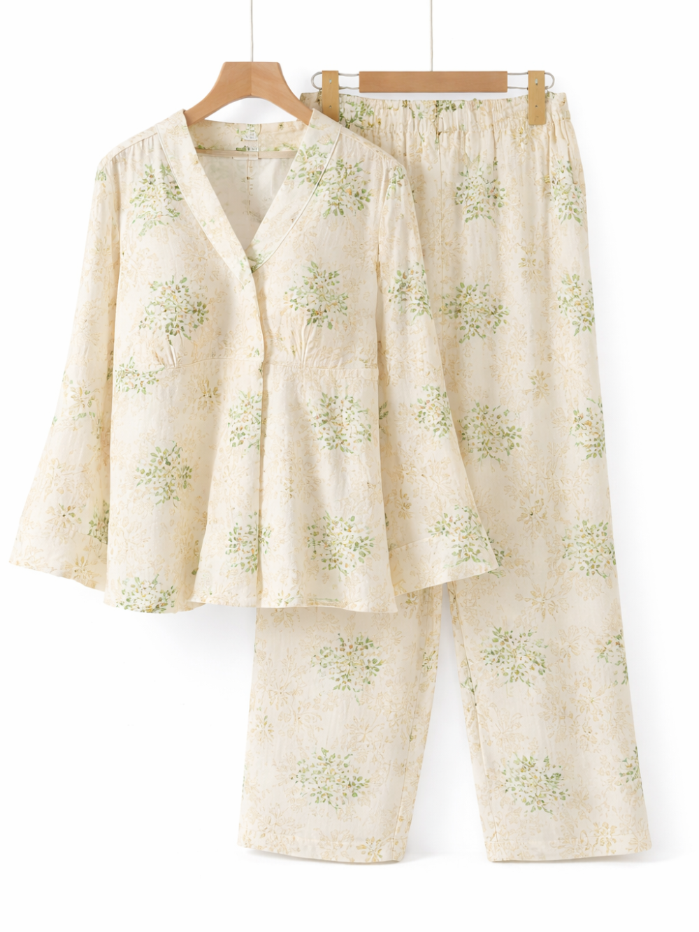 白背景のスタジオで撮影された、淡いクリーム色にグリーンの小花柄が入ったレディースルームウェア上下セット（長袖トップス＋ロングパンツ）
