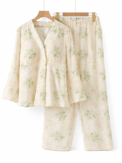 白背景のスタジオで撮影された、淡いクリーム色にグリーンの小花柄が入ったレディースルームウェア上下セット（長袖トップス＋ロングパンツ）
