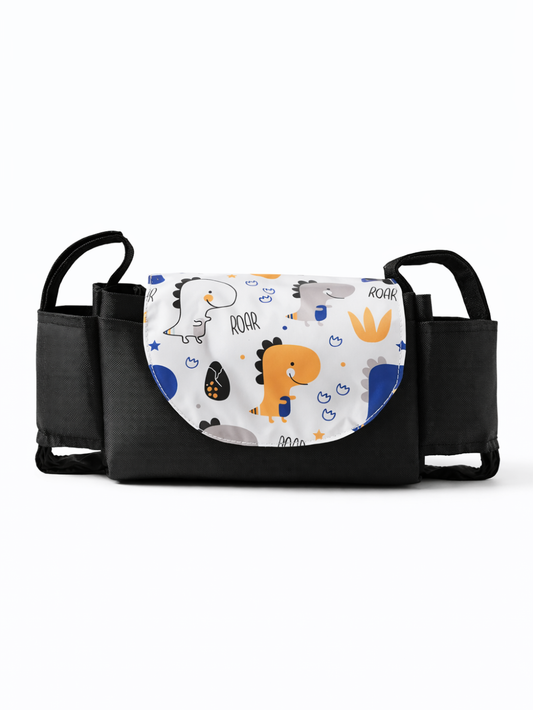 白背景のスタジオで撮影された、ブラックのベビーカー用オーガナイザー。前面フラップは恐竜柄で、「ROAR」の文字が入っており、両サイドにポケットと固定用ストラップが付いている。
