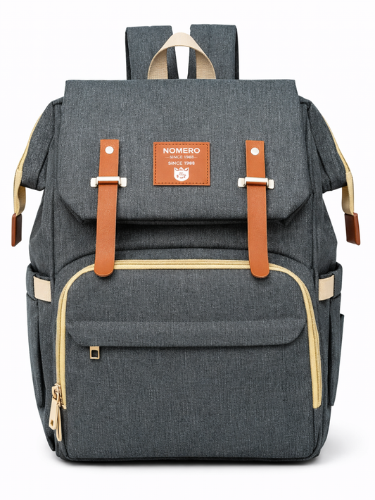 白背景のスタジオで撮影された、チャコールグレーのマザーズリュック。ブラウンのベルト留めと前面の大型ファスナーポケット、ゴールド系金具、サイドポケットが付いている。
