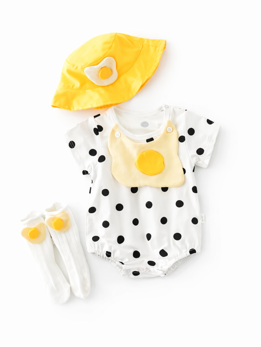 白背景に、ベビー用のコーディネートセットが平置きで配置されている。黒ドット柄のホワイトロンパース、目玉焼きモチーフのスタイ、目玉焼きワッペン付きのイエローハット、目玉焼きワンポイントの白ソックスが写っている。
