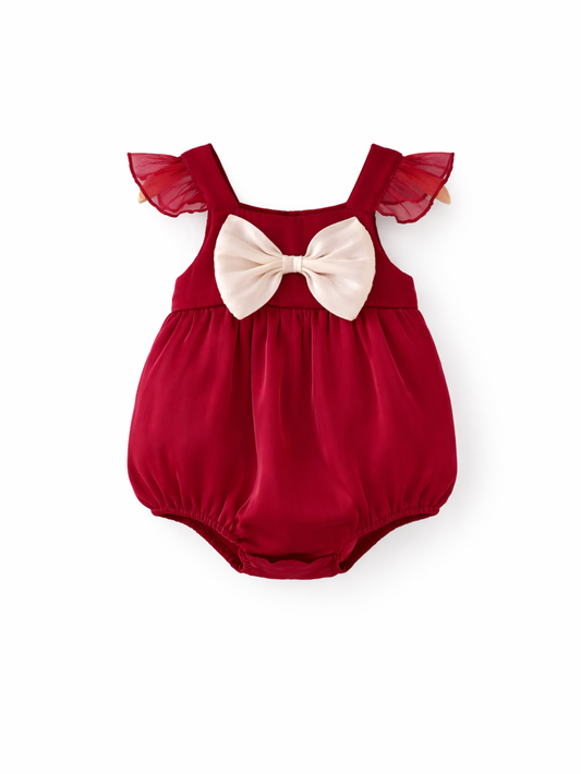 深い赤のベビーロンパース。透け感のあるフリル袖と、胸元のクリーム色リボンが特徴のスタジオ撮影（白背景）。
