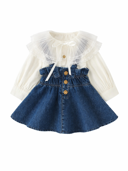 白いシフォン長袖ブラウス（大きなチュール襟・リボン付き）と、スマイルボタンが並ぶハイウエストのデニムスカートを組み合わせた女の子用セットアップの平置き商品画像（白背景）。
