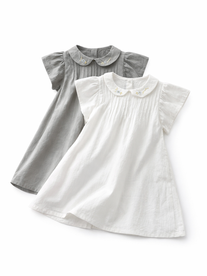 白い背景に、刺繍入りの襟とプリーツのある白いワンピースとグレーのワンピースが重ねて平置きされた商品写真。
