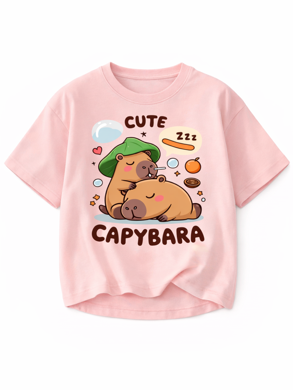 淡いピンクの半袖Tシャツ（クルーネック）。前面に、眠るカピバラ2匹のイラストと「CUTE CAPYBARA」の文字、ハートやフルーツなどの小さなモチーフがプリントされたデザイン。背景は白。
