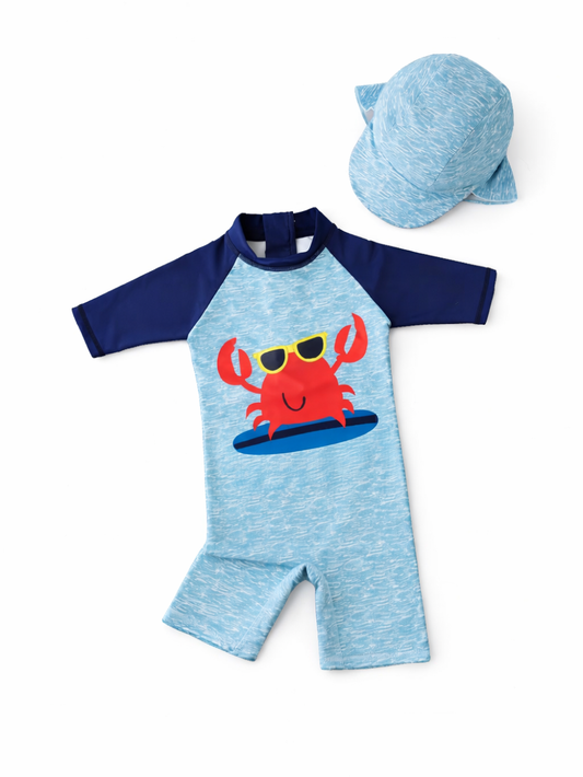 水色の杢調ボディにネイビーのラグラン袖、サングラスをかけた赤いカニ柄が入った子ども用ワンピース水着と同柄のキャップのセット（白背景）。
