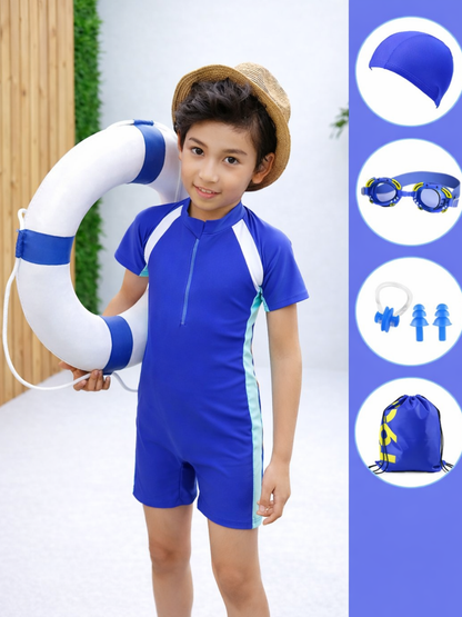 男の子が青い子ども用スイムスーツ（前ファスナー付き）を着用し、青いライン入りの白い救命浮き輪を持っている。麦わら帽子をかぶっている。右側にセット付属品の画像：青いスイムキャップ、ゴーグル、耳栓とノーズクリップ、青い巾着バッグ。背景は明るい屋外で、木製フェンスと緑の植物が見える。
