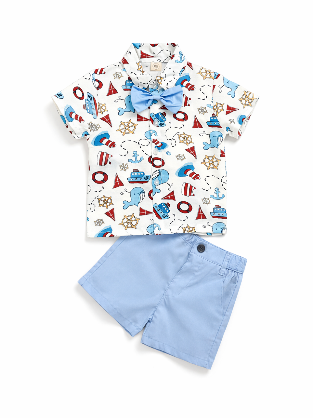 白背景のスタジオ撮影で、男の子用の上下2点セットをフラットに配置した商品画像。マリンモチーフ（船・イカリ・舵輪など）の総柄半袖シャツに、水色の蝶ネクタイ付き。ボトムはライトブルーのショートパンツで、ボタンとウエストゴム仕様。