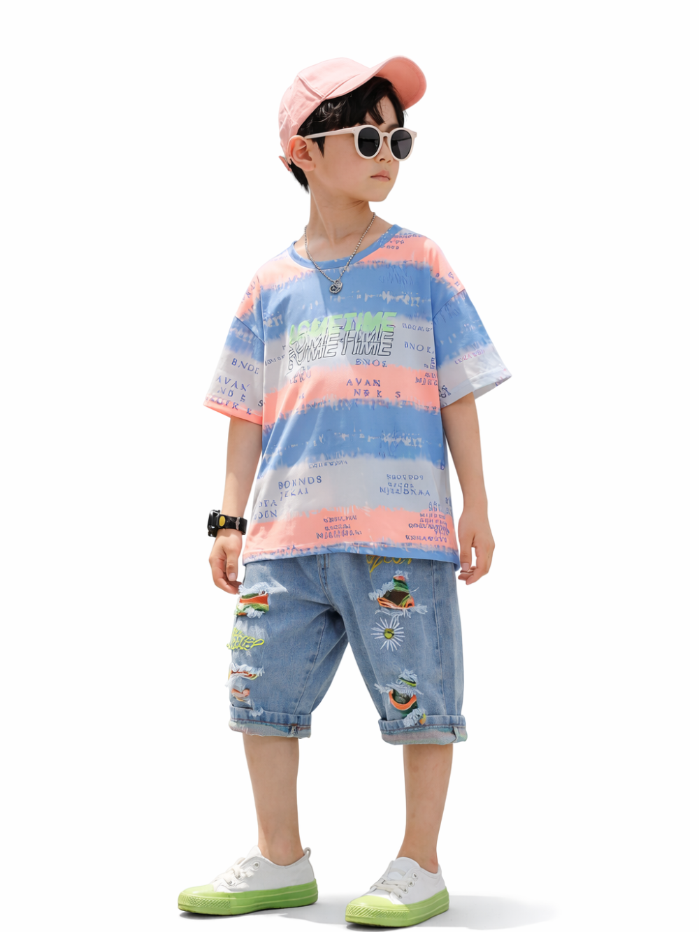 白背景スタジオで、ピンクのキャップと白いサングラスを着けた男の子が、パステル柄Tシャツと刺繍入りデニムハーフパンツ、白×グリーンのスニーカーを着用した全身写真。