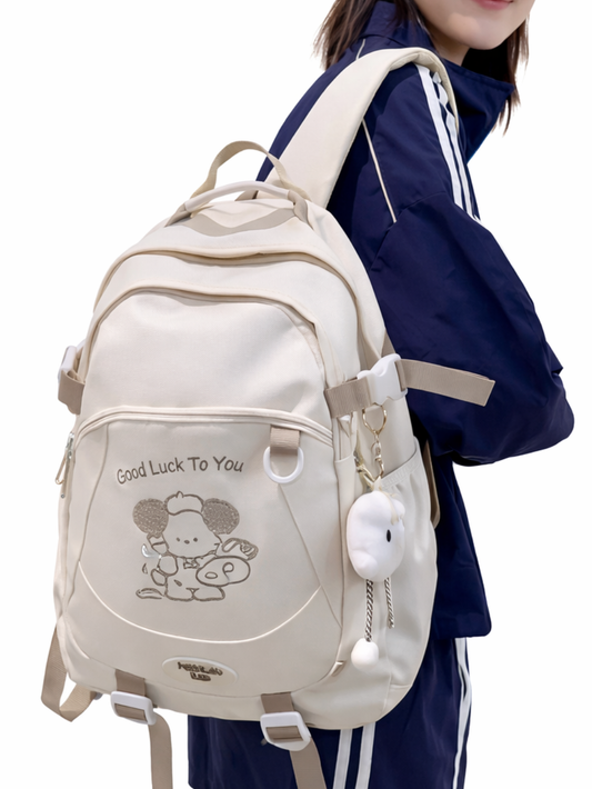 白背景で撮影した着用イメージ。ネイビーのスポーツウェアと黒キャップのモデルが、ベージュの大容量バックパック（くまのプリントとチャーム付き）を背負い、リュックが主役になる角度で見せている。