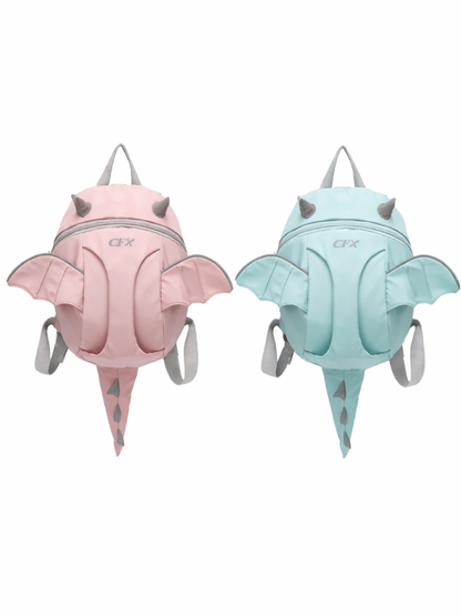 白背景に、ドラゴン（コウモリ風）の羽と小さな角、トゲ付きのしっぽが付いた子ども用リュックが2点、正面向きで並んでいる。左は淡いピンク、右は淡いミントブルーで、いずれもグレーの持ち手とショルダーストラップ付き。下に自然な薄い影が入っている。
