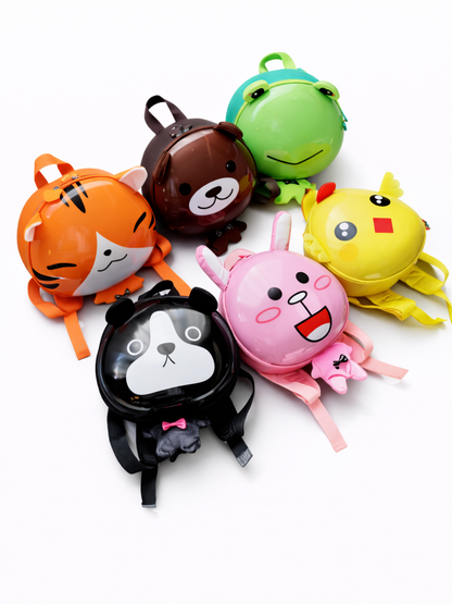 白背景に、ツヤのある動物モチーフの子ども用ミニリュックが6点並んでいる。トラ（オレンジ）、クマ（茶）、カエル（緑）、ヒヨコ（黄）、白黒の犬、ピンクのウサギのデザインで、丸いシェル型ボディと調節できるストラップが見える。下に自然な薄い影が入っている。
