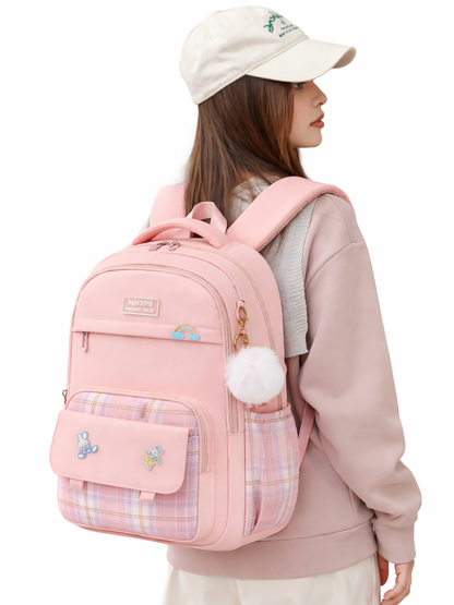 白背景で、ベージュのキャップをかぶった女性が、チェック柄ポケットと白いポンポンチャーム付きの淡いピンクのリュックを背負って横向きに立っている。