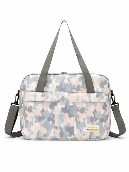 パステル調のカモフラージュ柄メッセンジャーバッグ（ショルダーストラップ付き）が、白いスタジオ背景に正面から単体で写っている。
