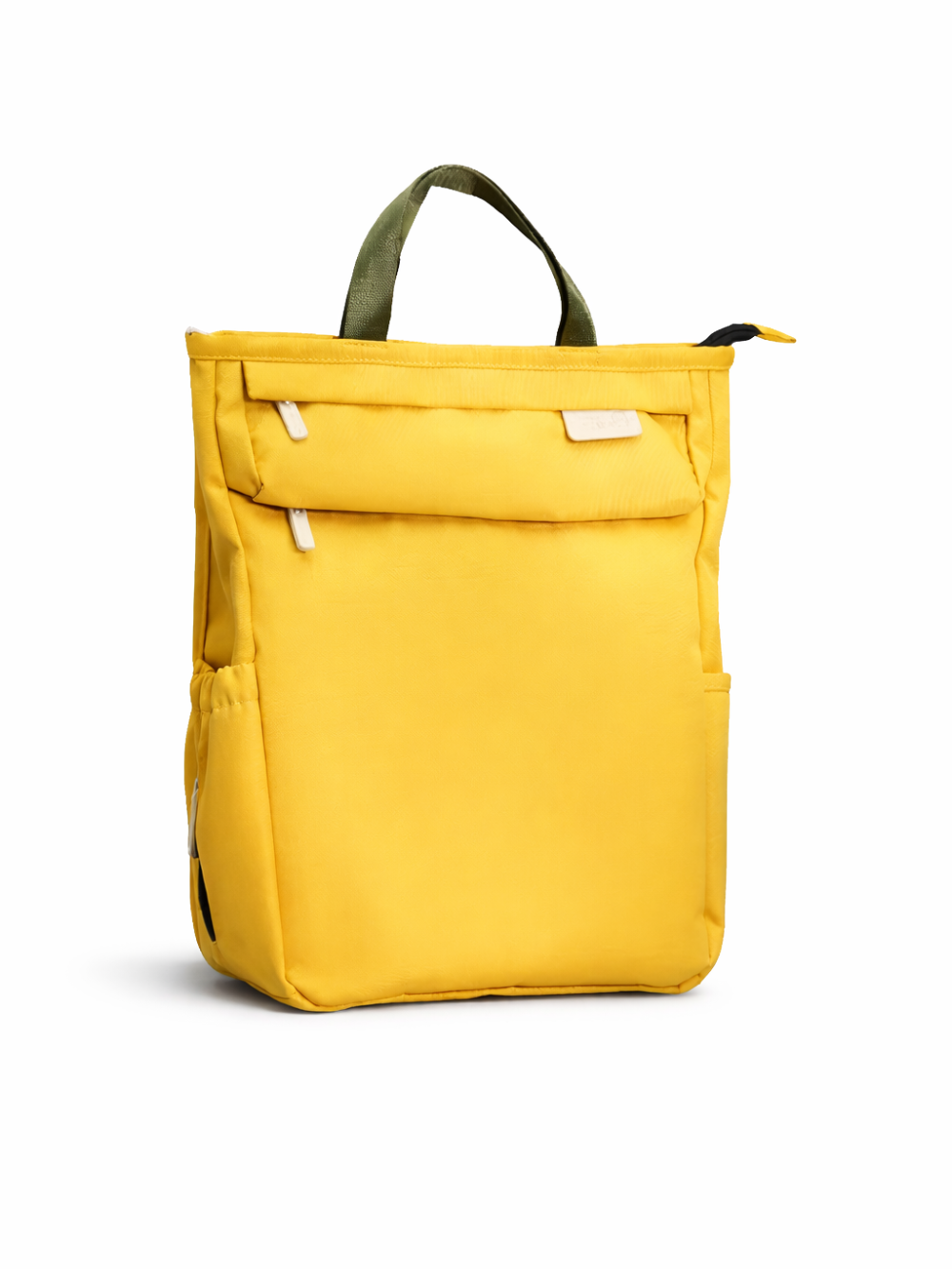 白い背景の上に、マスタードイエローのバックパックが正面から写っている。オリーブグリーンの持ち手と、白い引き手のファスナーポケット、側面ポケットがあり、底に自然な薄い影が落ちている。
