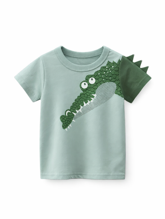 子ども用の半袖Tシャツ。淡いミントグリーンのボディに、前面へワニの立体風プリント。右袖は濃いグリーンで背びれのような三角スパイク付き。白背景で商品を正面から撮影。
