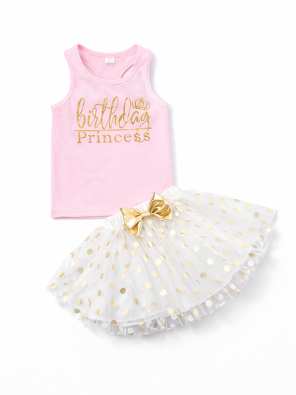 ピンクのノースリーブトップスと、ゴールドの水玉が入った白いチュチュスカートの女の子用2点セット。トップスには「birthday Princess」と王冠のプリントがあり、スカートのウエストにゴールドのリボンが付いている。白背景のスタジオ撮影。