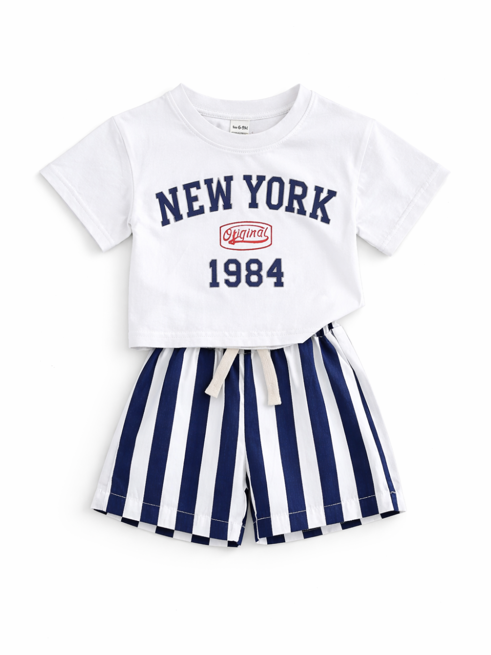 白背景に平置きされた子ども用2点セット。白い「NEW YORK 1984」ロゴ入りTシャツと、ネイビー×白の縦ストライプ柄ショートパンツ。