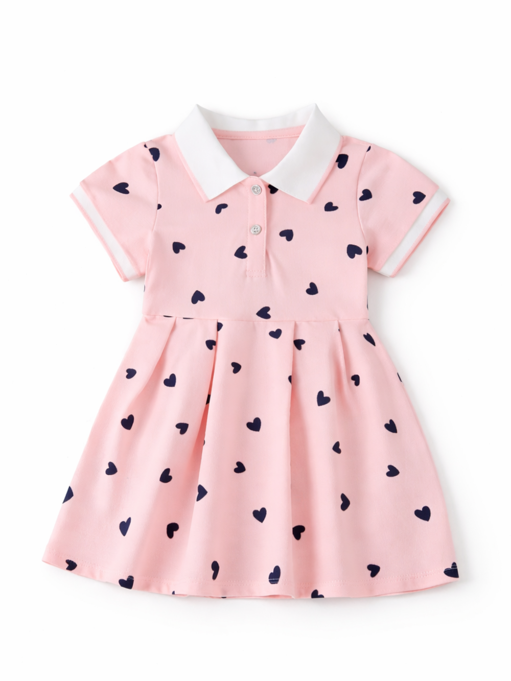 白背景のスタジオ撮影。ネイビーのハート柄が散りばめられた淡いピンクのベビー用ワンピース（白い襟・袖口、前ボタン付き）が正面から平置きで写っている。
