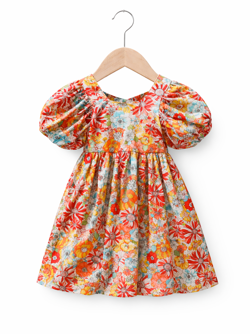 白背景に、木製ハンガーに掛かった子ども用ワンピース。赤・オレンジ・黄色・水色などのカラフルな花柄で、ふんわりしたパフスリーブとギャザーの入ったウエスト、広がるスカートが特徴。
