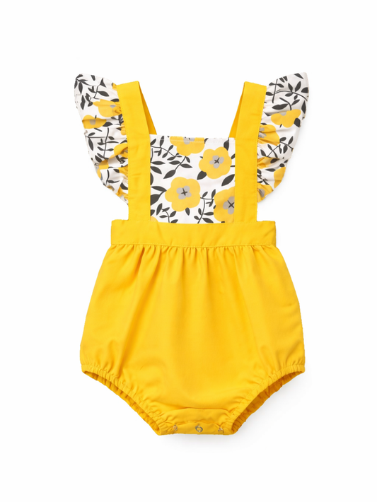 明るいイエローのベビーロンパース。白地に黄色い花と黒い葉柄のフリル袖と胸当て、太めの肩ひも付きで、ウエストと足口はゴム仕様。純白の背景に正面から単体で写っている。

