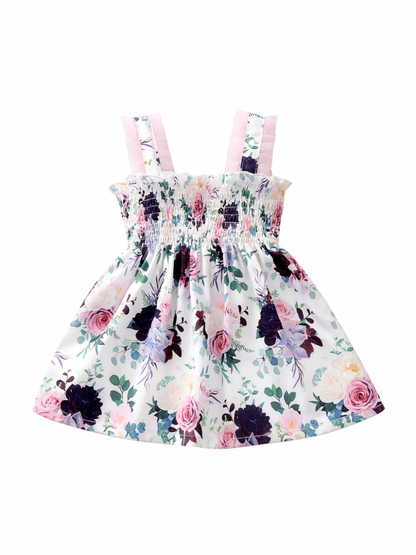 白背景に配置されたガールズ用ノースリーブワンピース。胸元はシャーリング仕様で、淡いピンクのフリルストラップ付き。白地にピンクのバラや紫・青の花、グリーンの葉が描かれた華やかなフラワープリント。
