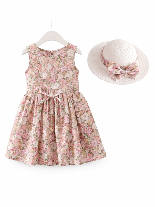 白背景に配置されたキッズ用ノースリーブワンピースと帽子のセット。ピンク系の花柄ワンピースはウエストにリボン付きで、ギャザーのフレアスカートデザイン。白い麦わら風ハットには同柄のリボン飾りが付いている。
