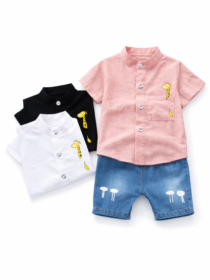 白い背景に、子ども用のスタンドカラー半袖シャツ3枚（ピンク、ブラック、ホワイト）とデニムショートパンツがフラットレイで配置されている。シャツには胸ポケットとキリンのワンポイントがあり、ショートパンツの裾付近に白いプリントが入っている。
