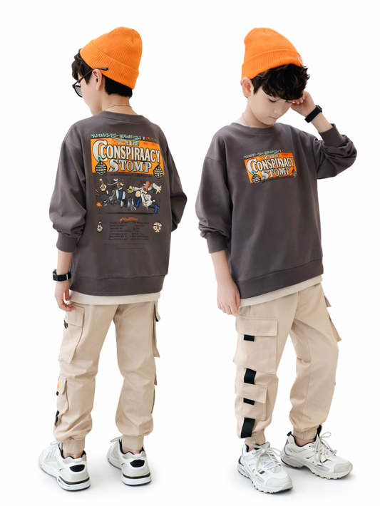 白い背景に、オレンジのニット帽をかぶった男の子が2人並んで立っている。グレーのスウェットとベージュのカーゴパンツ、白いスニーカーを着用。左の子は後ろ向きで背中の大きなプリントが見え、右の子は正面寄りで帽子に手を添えるポーズをしている。
