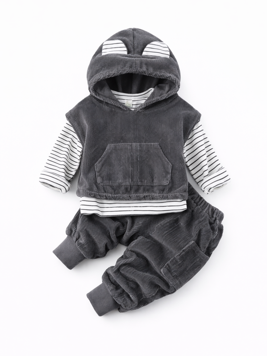 白い背景に、ダークグレーのコーデュロイ素材フード付きトップスと同素材のパンツを合わせた子ども用セットがフラットレイで配置されている。フードにはボーダー柄の耳モチーフが付き、インナーとして白×黒ボーダーの長袖トップスが重ねられている。トップス前面にカンガルーポケットがある。
