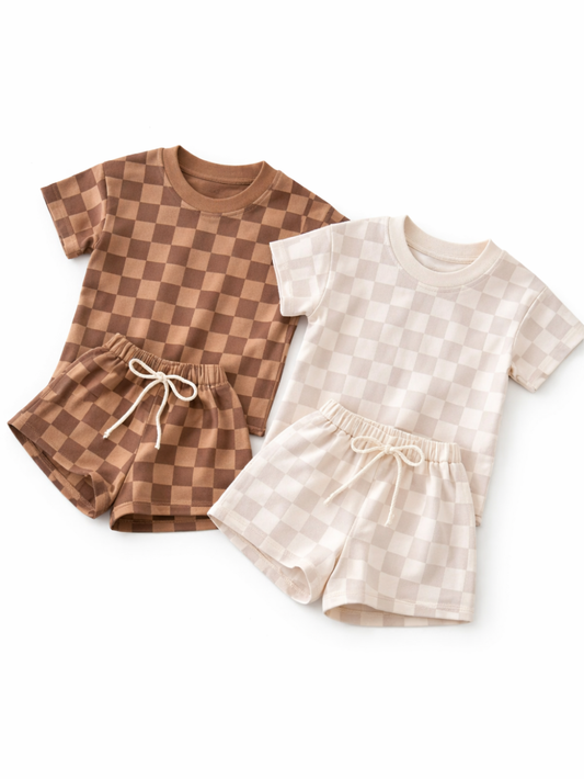白背景に、チェック柄のキッズTシャツ＆ショートパンツのセット2組（ブラウン系とアイボリー系）が並べて置かれている。ショーツはウエストゴムで紐付き。