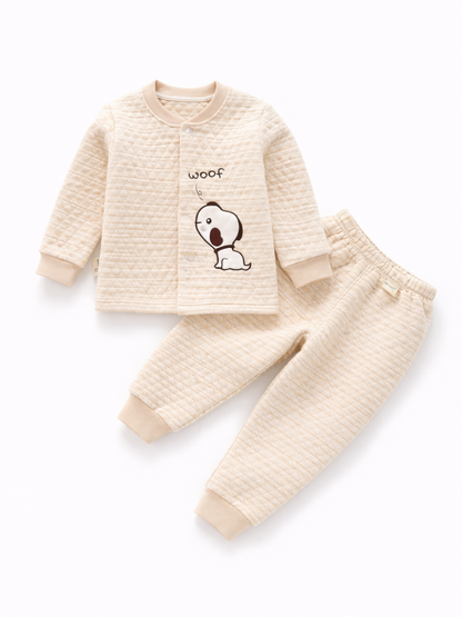 生成り色のキルティング生地のベビー用上下セット（長袖トップスとパンツ）。トップスに「woof」と犬のイラストがあり、白背景に平置きで撮影されている。
