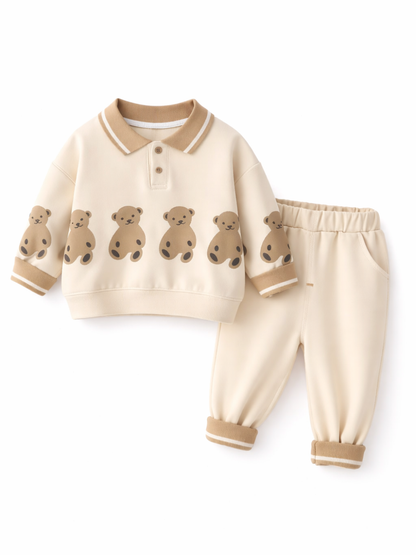 白背景に、ベージュの襟付きトップス（裾にクマ柄プリント）と同色ジョガーパンツのベビー用上下セットが並んでいる。
