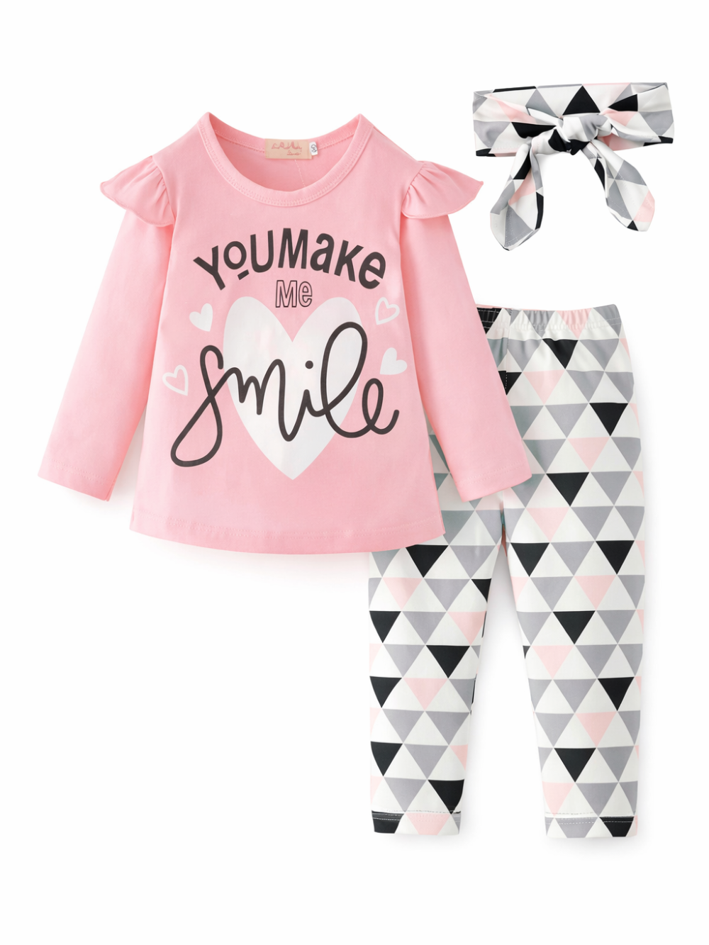 白背景のスタジオ風に、女の子用3点セットが並べて撮影されている。フリル袖のピンク長袖トップスはハート柄と「You make me Smile」プリント入りで、グレー・ブラック・ピンクの三角柄レギンス、同柄のリボンヘアバンドがセットになっている。
