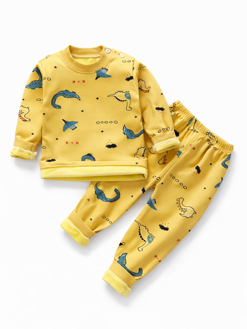 グレーの背景に、イエローの恐竜プリントが入った子ども用長袖トップスとロングパンツの上下セットを平置きした商品写真。袖口と裾は折り返し仕様で、周囲に小物が少し配置されている。
