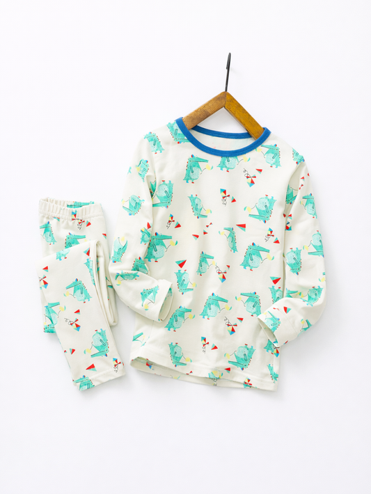 白背景に、木製ハンガーに掛けたキッズ用長袖パジャマ（オフホワイト×青い襟、恐竜とカラフルな三角柄）と、横に置いた同柄のパンツが写っている。
