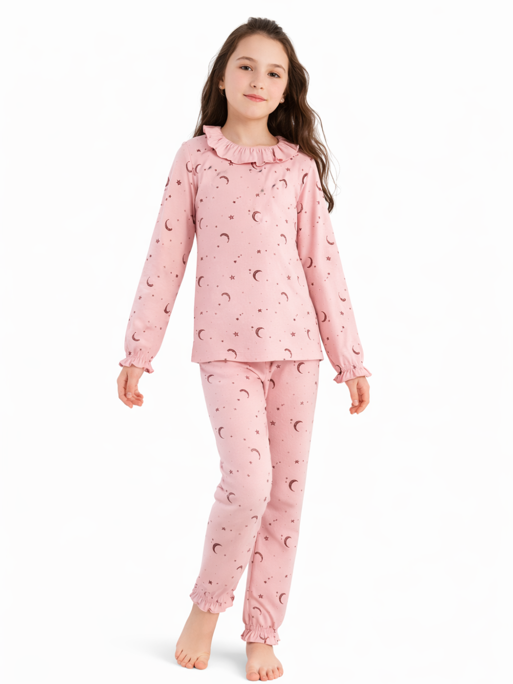 白背景のスタジオで、月と星柄のピンクの長袖パジャマ上下を着た女の子が、自然な微笑みでカタログ風に立っている全身写真。
