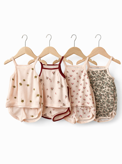 木製ハンガーに掛けられた、淡いピンク系のベビー用キャミソール＆ショートパンツ4点セット（リブ素材・小花柄やボタニカル柄）を白背景で撮影した商品写真。
