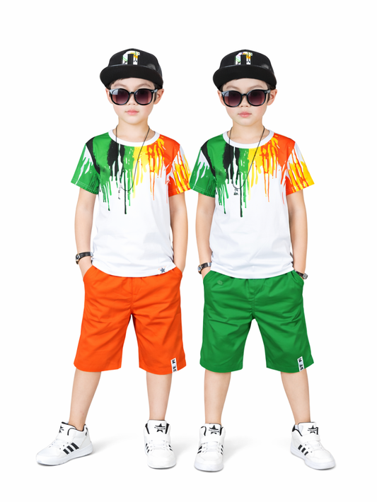 白背景のスタジオで、双子の男の子2人が中央に並んで立つ。黒いキャップとサングラスを着用し、ペイント柄プリントの白Tシャツに、オレンジのショートパンツ（左）とグリーンのショートパンツ（右）、白いスニーカーを合わせたコーデ。
