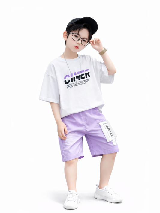 白背景のスタジオ撮影風。白い「CHIMER」ロゴ入りTシャツにラベンダーのショートパンツ、黒いキャップと黒縁メガネ、ネックレスと腕時計を着用した男の子が、メガネに手を添えて立っている。白いスニーカーと足元まで全身が写っている。
