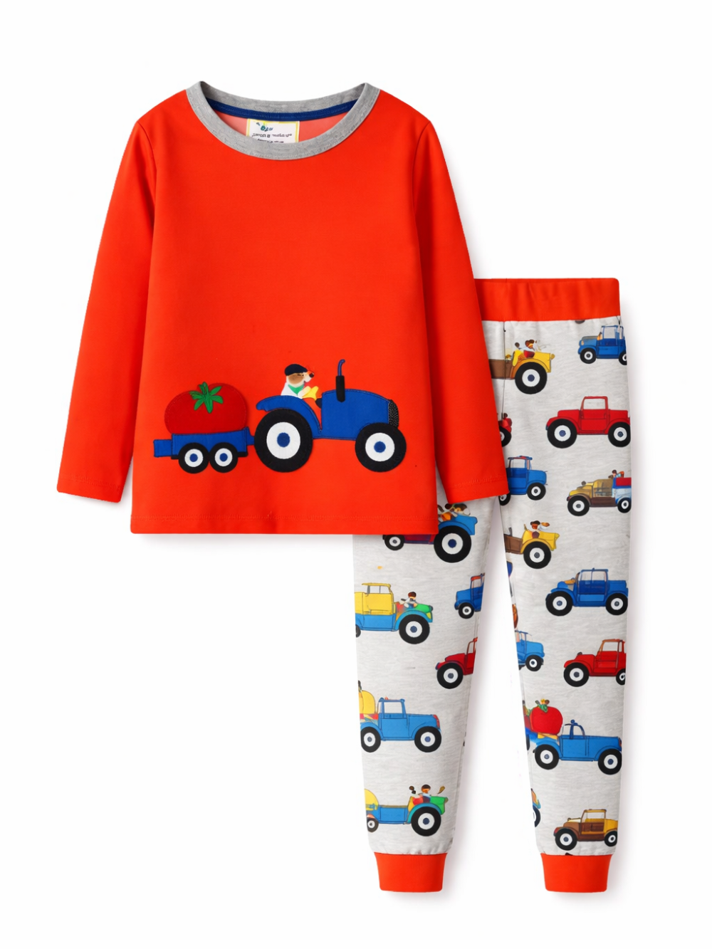 白背景のスタジオ撮影で、子ども用長袖パジャマ上下セットを正面から配置。赤いトップスに青いトラクターのアップリケ、グレーのパンツはトラクター柄で裾とウエストが赤。
