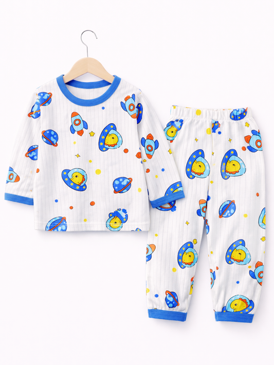 白背景のスタジオ風商品写真。子ども用の長袖パジャマ上下セットが並べて配置されている。左にトップスが木製ハンガーに掛けられ、白地に細いストライプのリブ風生地、青い襟ぐりと袖口のトリム。ロケット、UFO、星などの宇宙モチーフがカラフルにプリントされている。右に同柄のロングパンツが置かれ、ウエストはゴム仕様で、裾は青いリブ切り替え。
